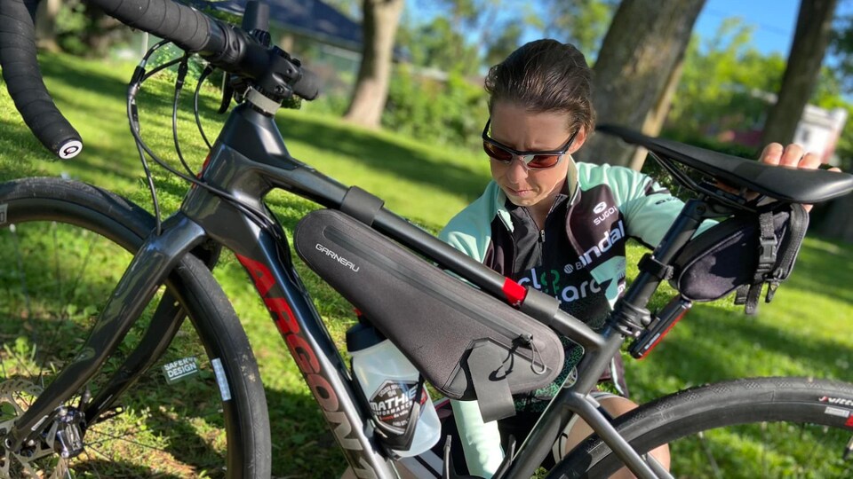 Marielle Bouchard s'accroupit pour effectuer des vérifications sur son vélo. 