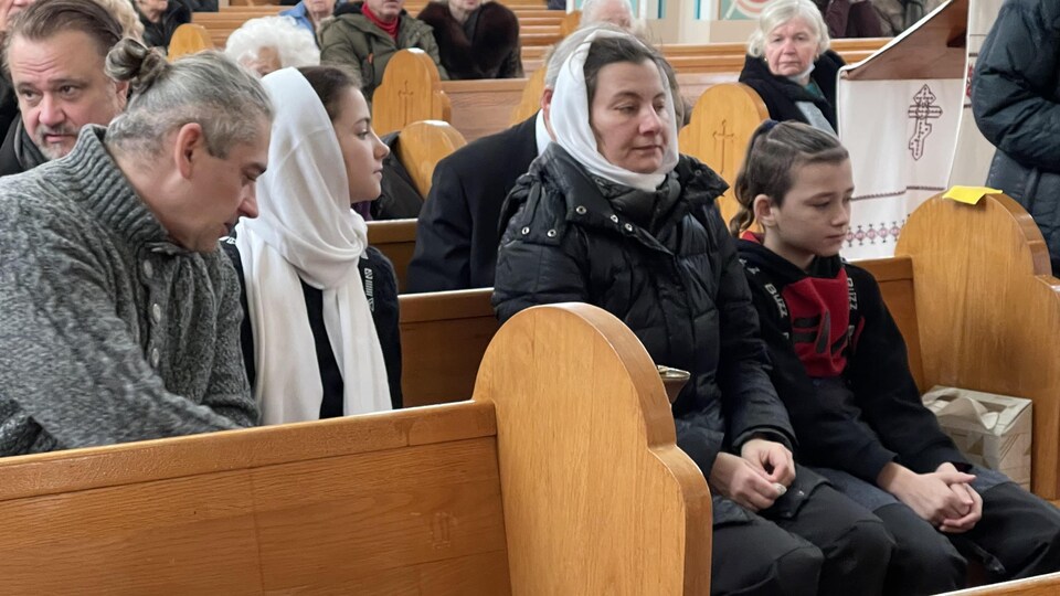 Les parents de Mariia Legenkovska et leurs deux enfants assis dans la cathédrale, l'air stoïque.
