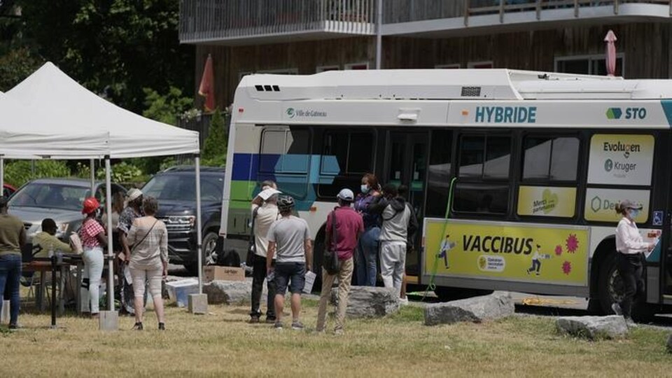 Des gens font la file devant un autobus stationné.