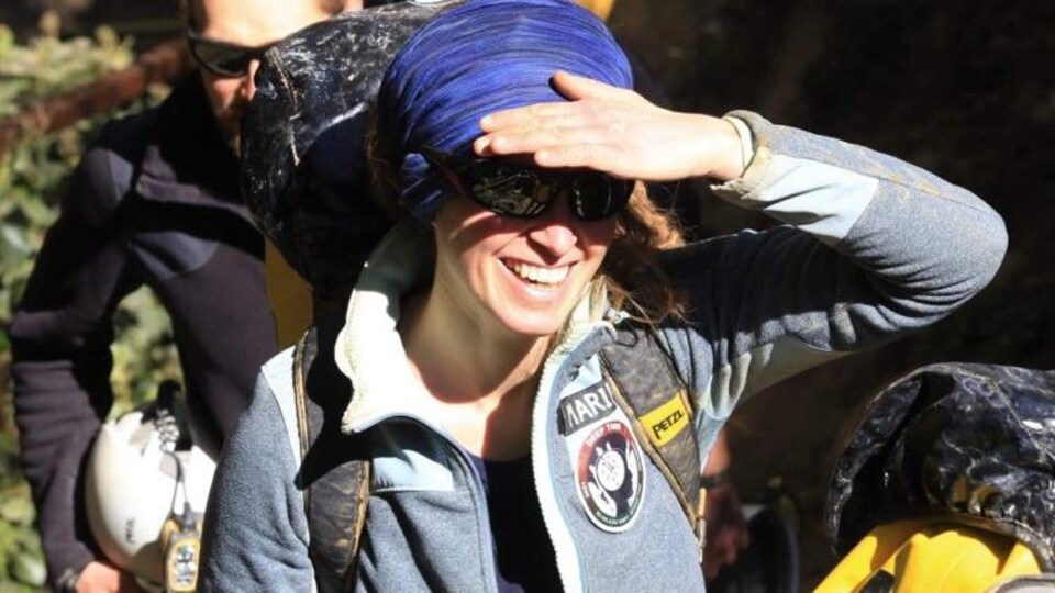 Une jeune femme souriante se cachant du soleil avec sa main.