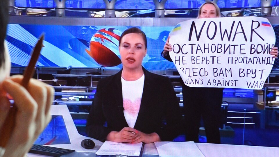 Marina Ovsianikova, bir TV şovunun setinde bir tabela tutuyor.