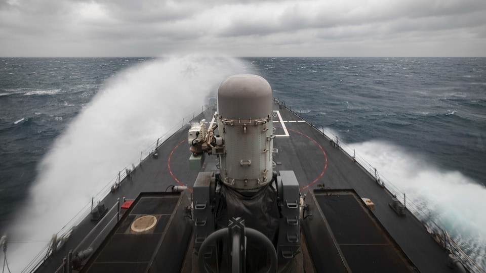 Le USS John S. McCain, un destroyer à missiles guidés de la marine américaine, provoque des gerbes d'eau en naviguant en mer.