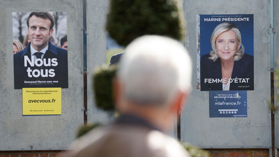 A man looks at the posters of two politicians. 