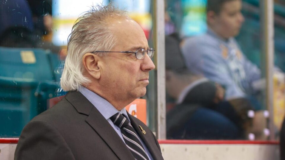 Photo de Mario Durocher de profil, qui regarde les joueurs sur la glace.