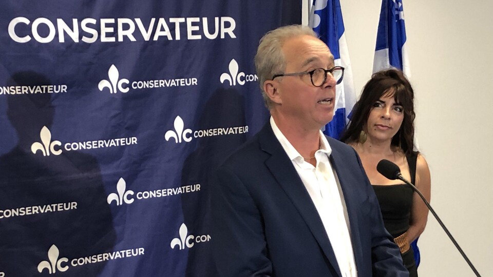 Mario Fortier parle à un micro lors de l'annonce de sa candidature, la candidate conservatrice Anne Casabonne se tient à côté de lui.