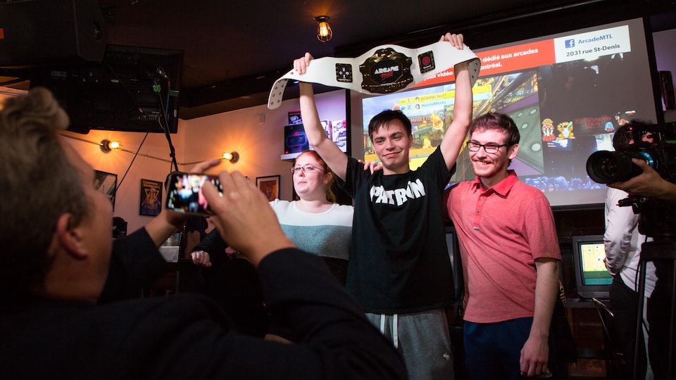 Félix Locas soulève la ceinture de champion remise au vainqueur du tournoi.