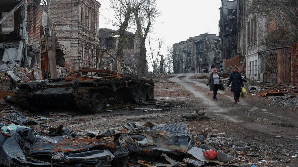 Un char d'assaut endommagé traîne parmi les décombres dans une rue.