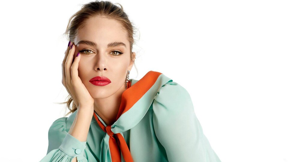 La femme porte une blouse bleue et orange.