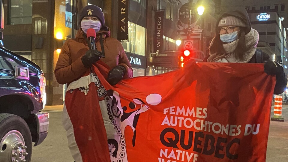 Deux femmes tiennent un drapeau de Femmes autochtones du Québec.