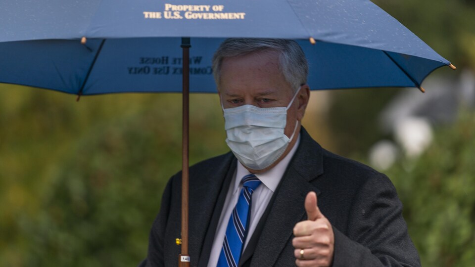 Mark Meadows tenant un parapluie dans sa main, portant un masque.