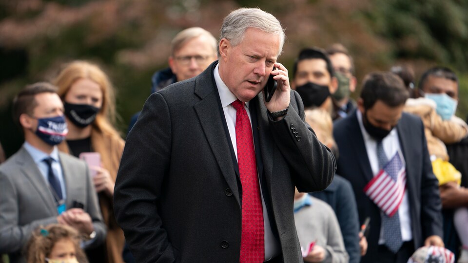 Mark Meadows, dehors lors d'un rassemblement, parle au téléphone avec des gens en arrière-plan.