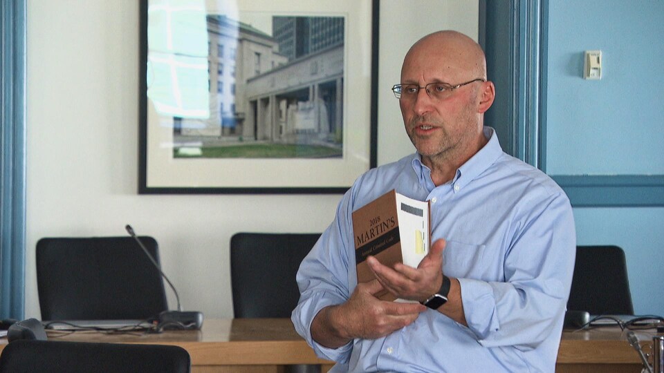 Un homme donnant une présentation et tenant un livre de droit.