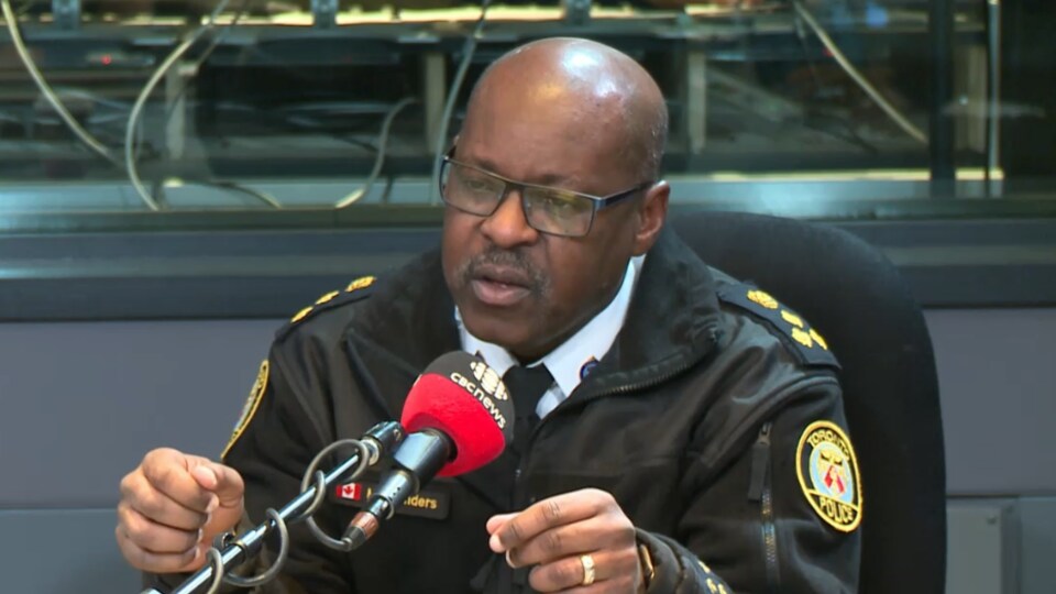 Photo d'un homme portant un uniforme de policier derrière un micro dans un studio de radio
