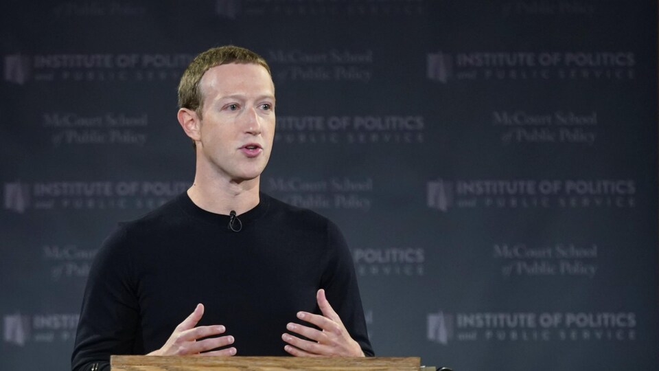 Mark Zuckerberg, debout derrière un lutrin en bois, s'adresse à une foule.