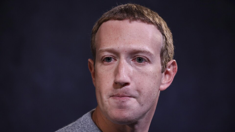 L'homme est vêtu d'un polo gris.