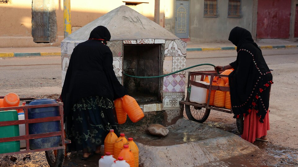 Femmes marocaines remplissant des contenants d'eau dans le sud du Maroc.
