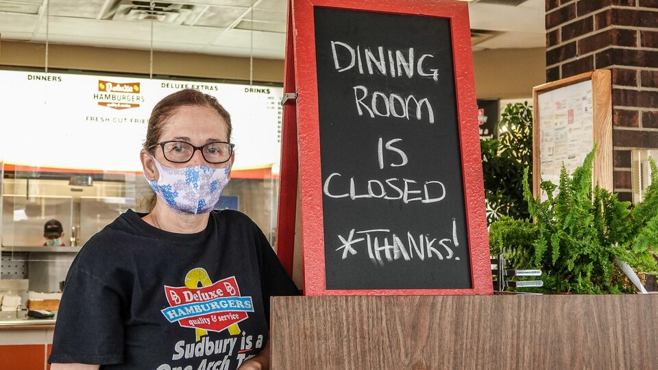 Marsha Smith à côté d'une affiche qui indique que la salle à manger est fermée.