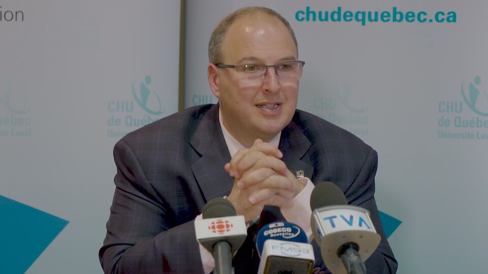 Martin Beaumont en conférence de presse parle devant plusieurs micros en se tenant les mains.