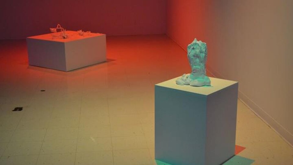 Une oeuvre en posée sur un cube dans une salle d'exposition.