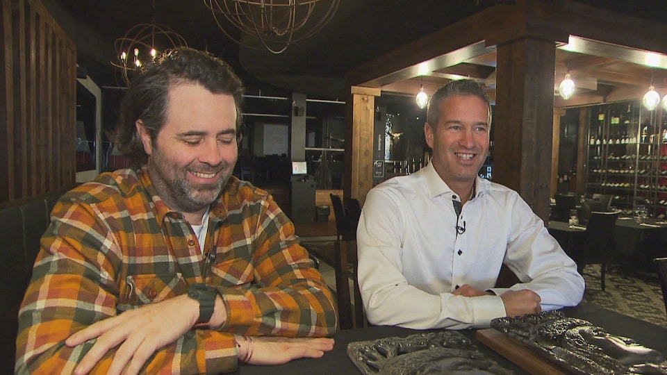 Les deux hommes, souriants, assis à une table du restaurant.