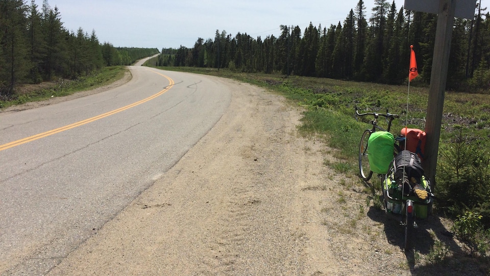 Le vélo appuyé contre un poteau, face à la route.