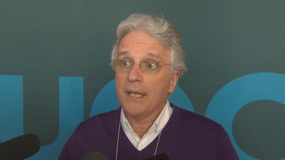 Martin Robitaille, le directeur du département des sciences sociales de Université du Québec en Outaouais, s'adresse aux médias. Il porte des lunettes, une chemise et un chandail. 