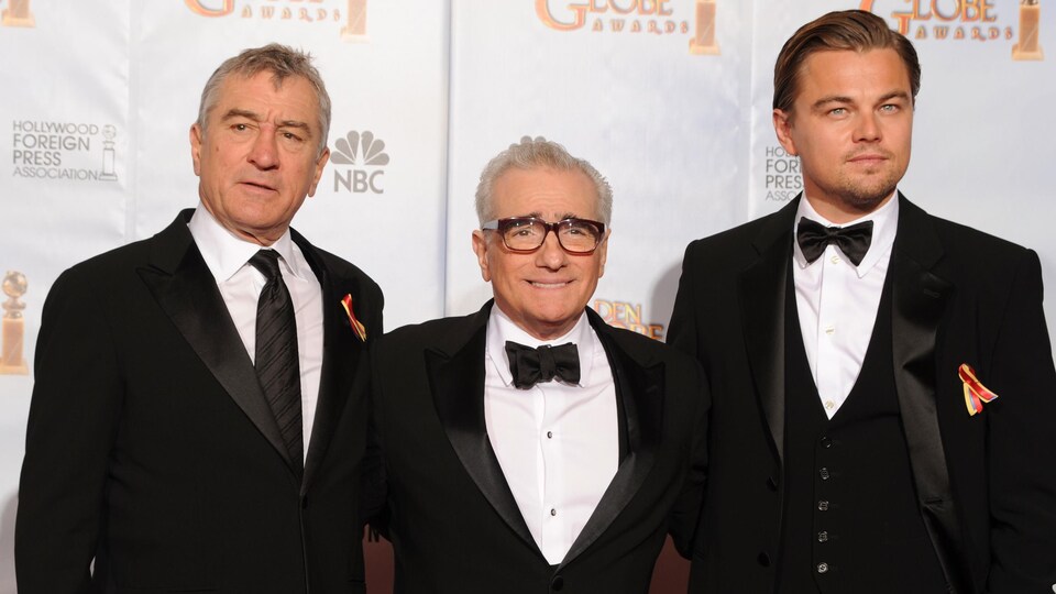 trois hommes en tuxedo posent sur le tapis rouge d'un gala de cinéma. 