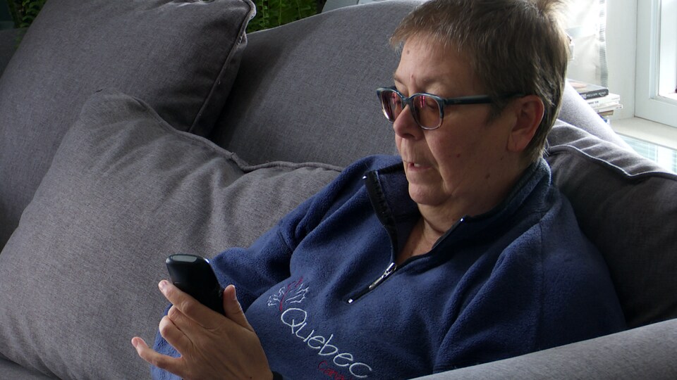 Martine Lévesque tient un téléphone dans ses mains.