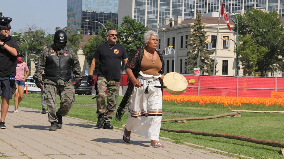 Mary Starr marche tambour à la main sur le terrain du Palais législatif du Manitoba le 26 août.