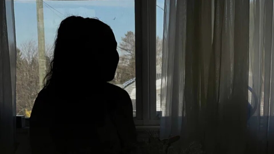 La silhouette d'une femme devant une fenêtre.