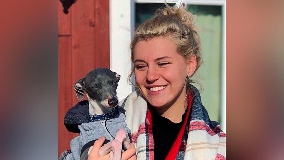 Marylène Levesque souriante, tient un petit chien dans ses bras.