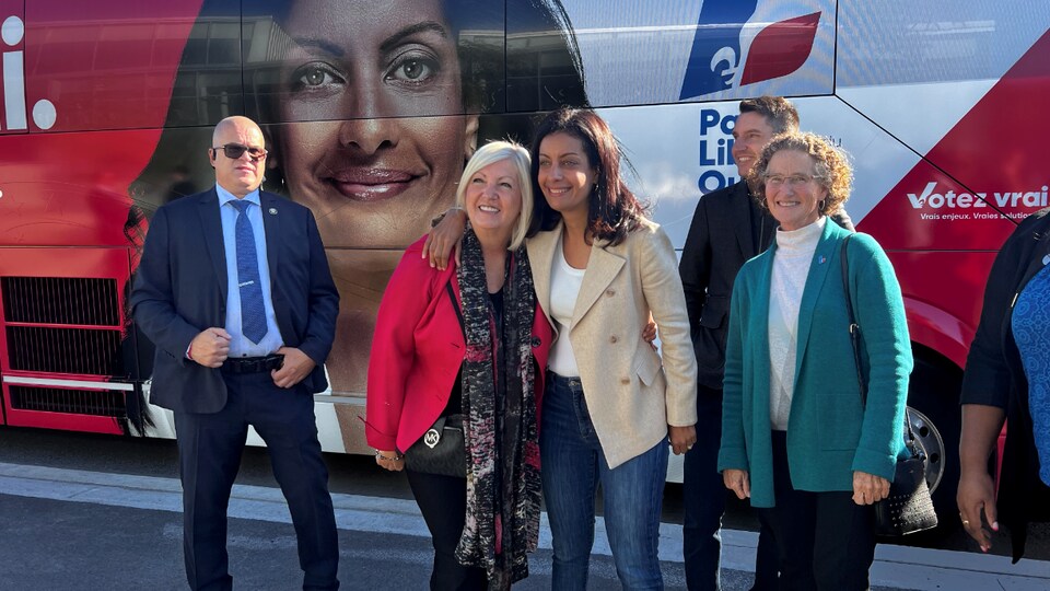 Des candidats libéraux devant l'autobus.