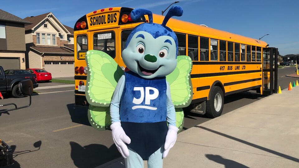 Une mascotte devant un autobus scolaire.