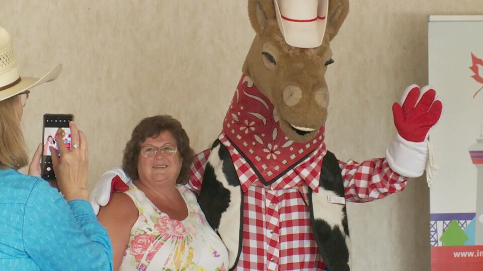 Une personne se fait prendre en photo avec la mascotte du Stampede de Calgary (juin 2022).