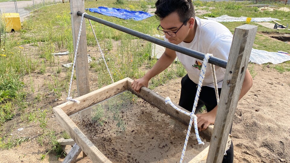 Un jeune homme cherche des artefacts sur un site archéologique.
