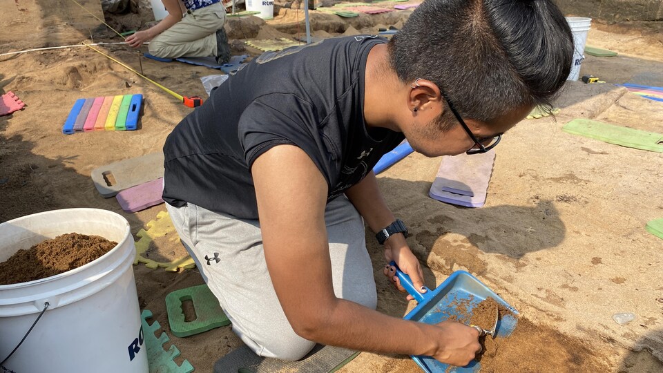 Un jeune homme gratte le sol en quête d'artefacts.