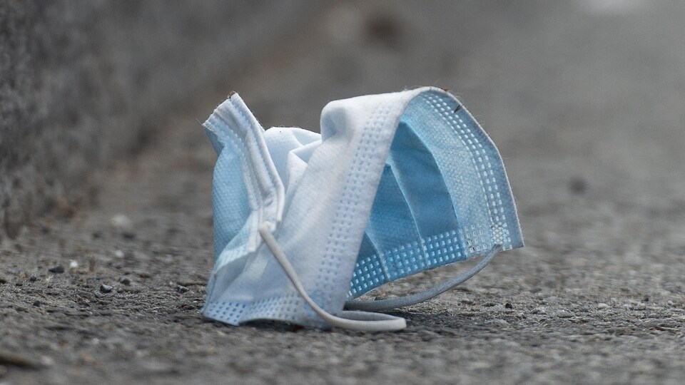Un masque jetable traîne dans la rue.