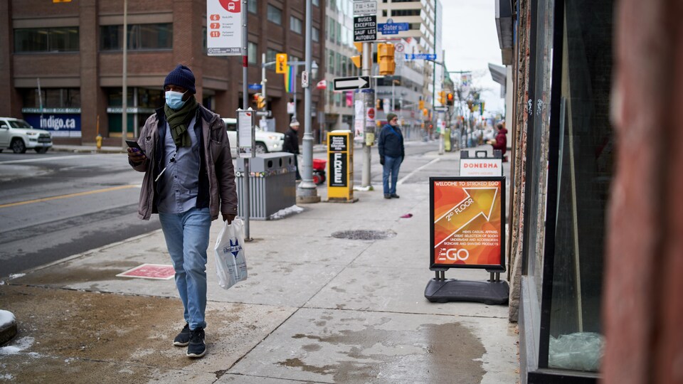 Un homme marche en portant un masque au centre-ville d'Ottawa.