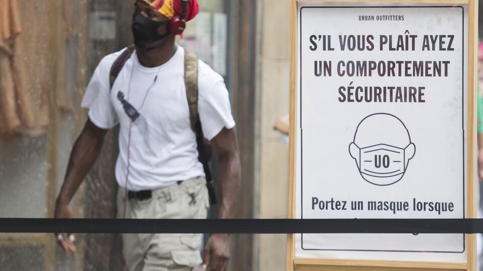 Une pancarte demande aux clients du magasin de porter un masque.