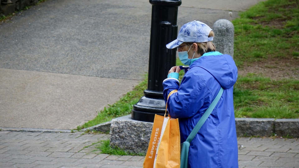 Une personne portant un masque marche sur le trottoir.