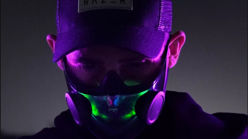Un homme avec une casquette porte un masque intelligent lumineux dans la nuit. 