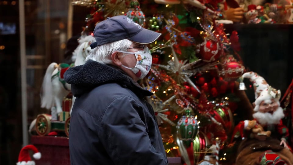 Un homme le visage couvert d'un masque passe devant la vitrine d'un magasin décorée d'un sapin de Noël, le 11 novembre 2020 à Budapest, en Hongrie.