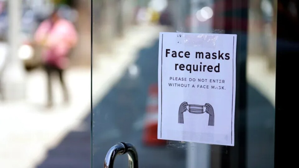 Affiche sur une porte qui rappelle le port du masque obligatoire.