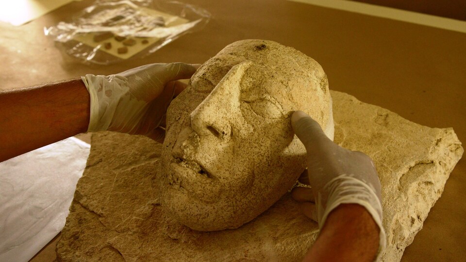 Des mains tiennent le masque du souverain maya Pacal le Grand.
