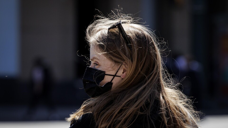 Femme de profil, portant un masque noir, dans la rue à Toronto le 12 avril 2022.