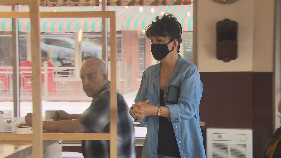 Une dame entre dans un restaurant en portant son masque.