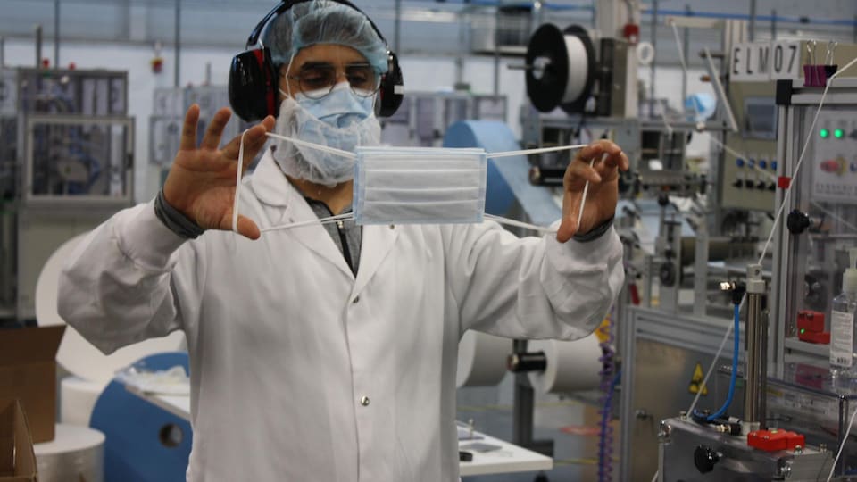 Un homme montre un masque dans une usine.