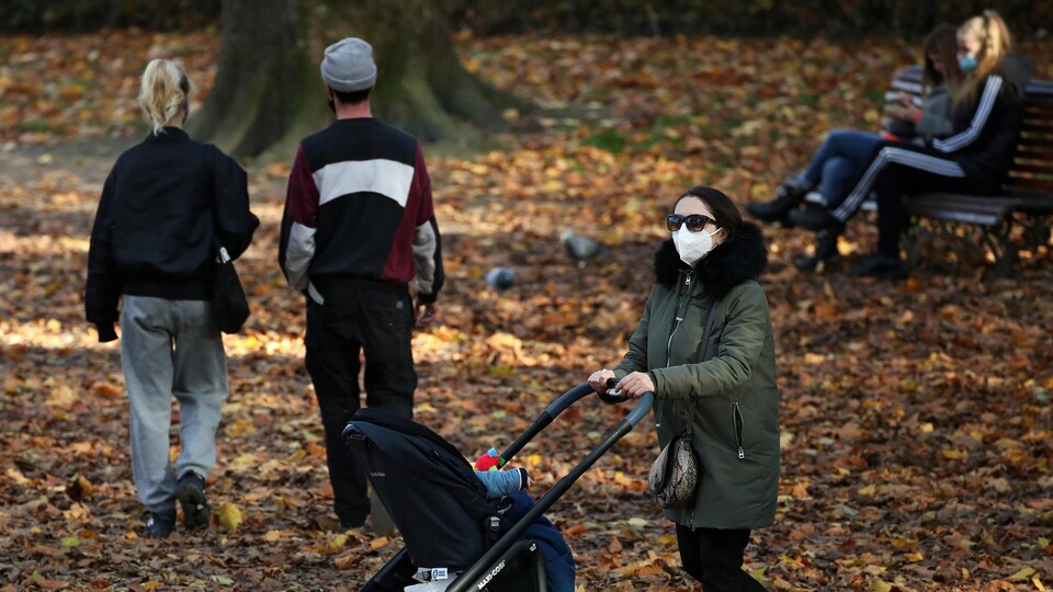 Des gens dans un parc, en automne, portant le masque.