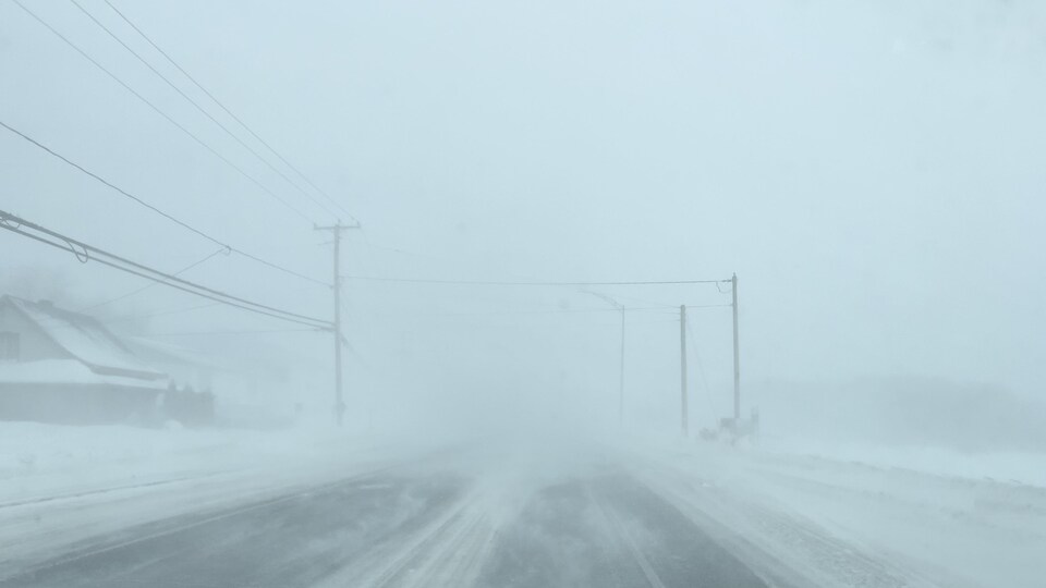 Un rue déserte, assombrie et brouillée par les forts vents qui déplacent la neige. 