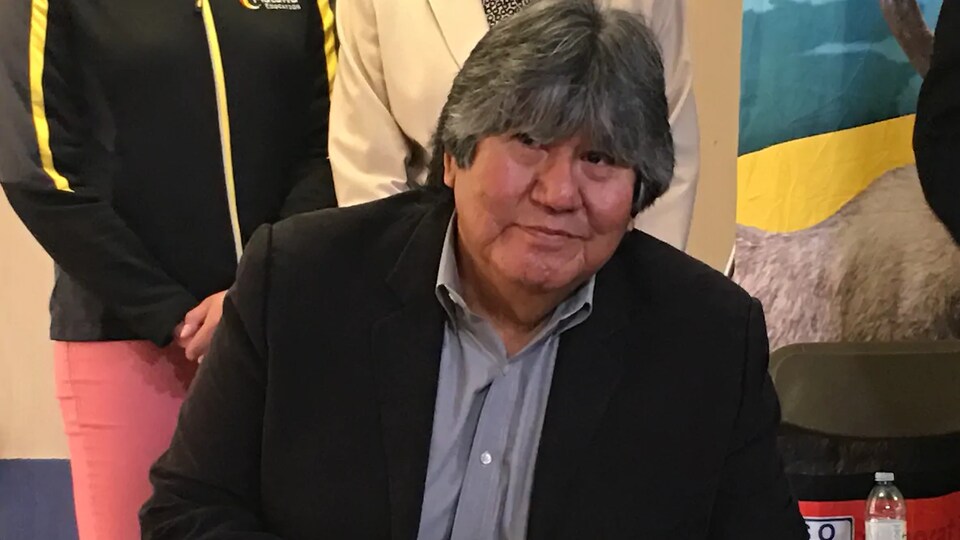 Un homme autochtone en train de signer un document.